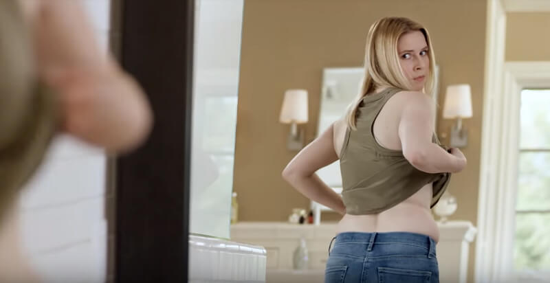 woman looking at her belly fat in the mirror