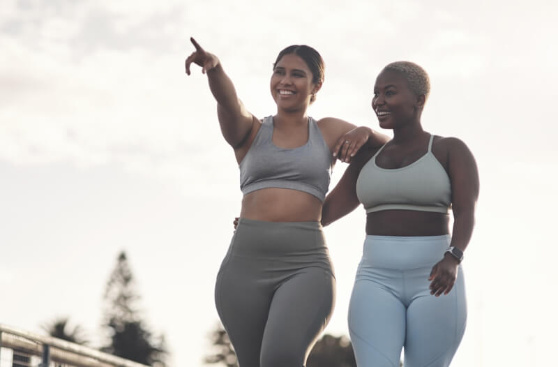 Two woman smiling while on foot in joggers