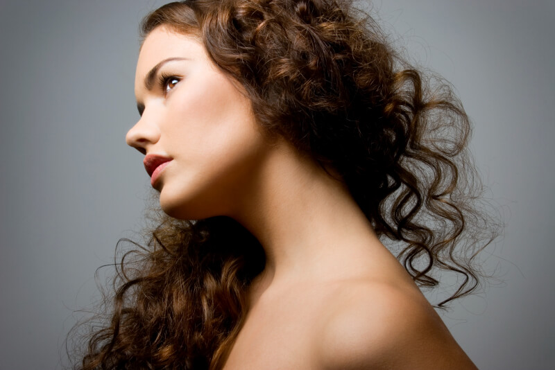 Woman with curly hair tilted right showing her face, chin and part of body