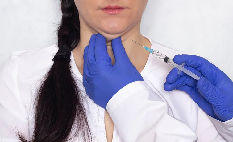 A woman being injected in the fat below the chin.